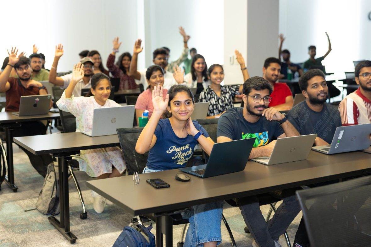 Students sitting in class raising their hands.